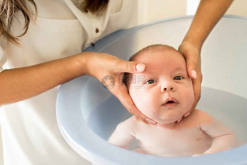 可爱的新生婴儿由母亲洗澡图片