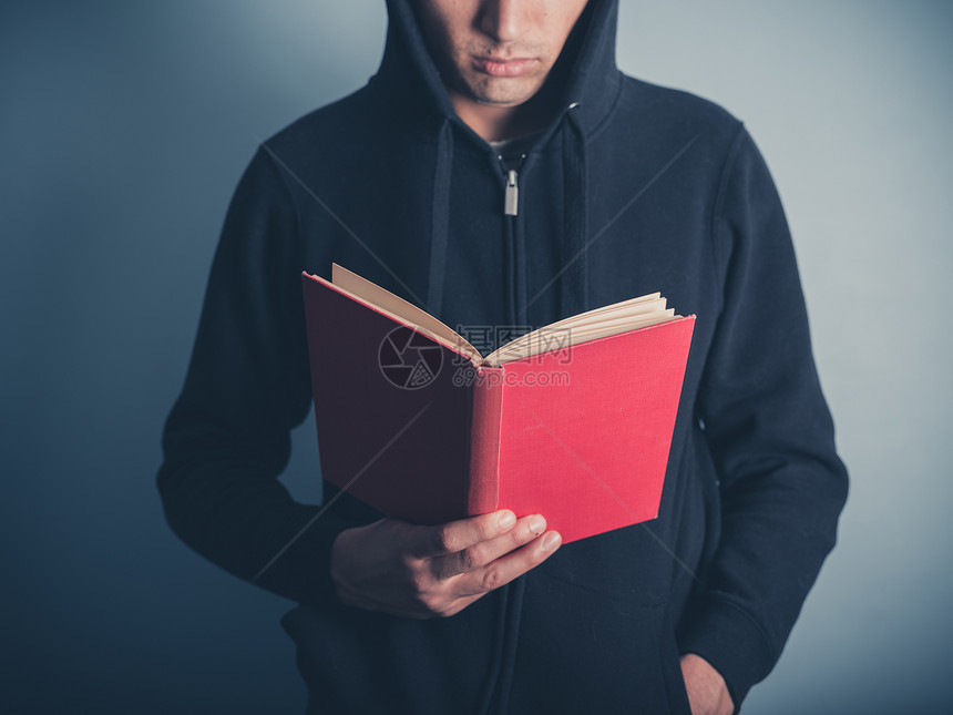 个戴着头巾的轻人站周围,正读本红色的书图片