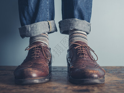 穿着条纹袜子皮鞋站木地板上的男人的脚背景图片