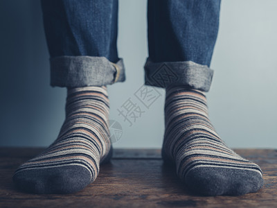青色竖条纹穿着条纹袜子站木地板上的男人的脚背景