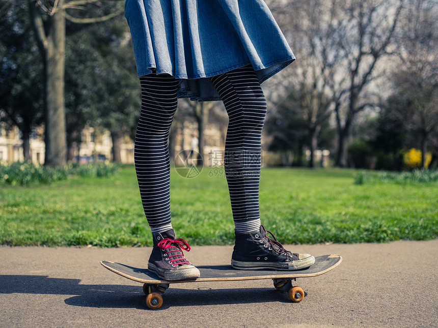 个穿着时髦衣服的轻女人正公园里玩滑板图片