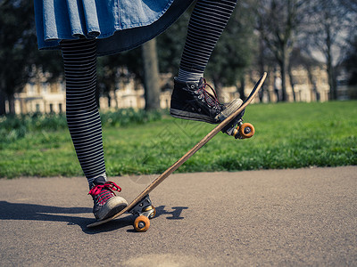 个穿着时髦衣服的轻女人正公园里玩滑板图片