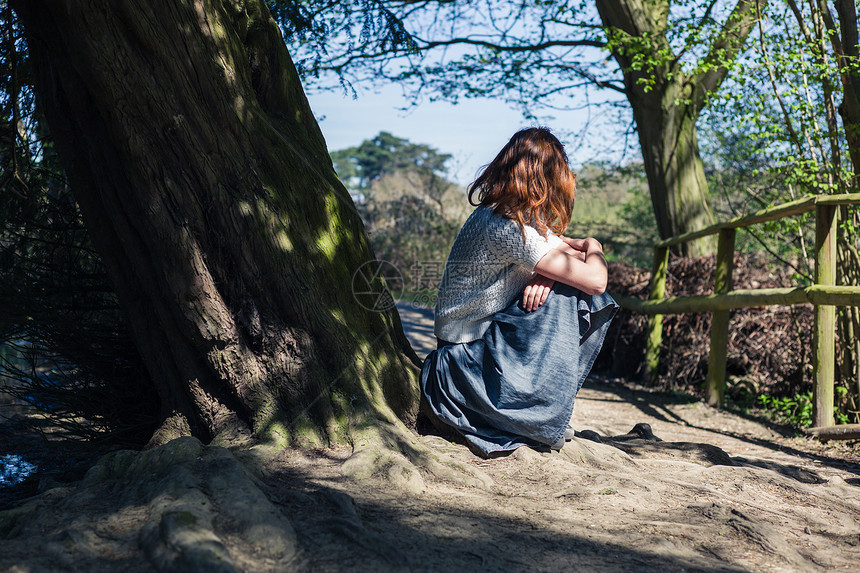 个轻的女人坐森林里水边的棵树下图片