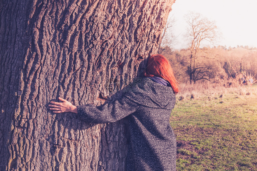 个轻的女人寒冷的冬天拥抱棵大树图片