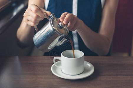 个轻的女人正餐馆里给自己倒杯咖啡背景图片