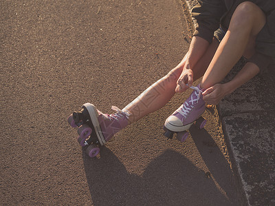个轻的女人坐地上,日落时公园里穿上溜冰鞋图片