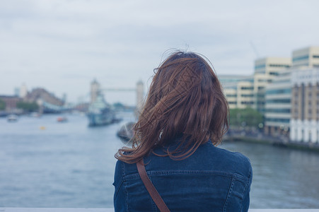个轻的女人站座桥上,欣赏泰晤士河伦敦的天际线图片
