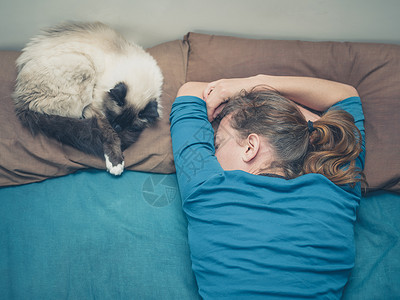 个轻的女人睡张床上,旁边只猫图片