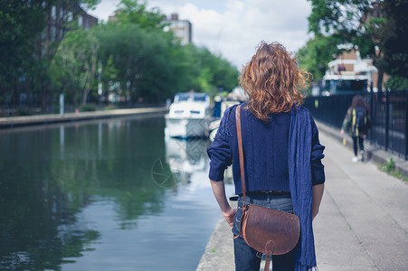 个轻的女人站城市的条运河旁图片