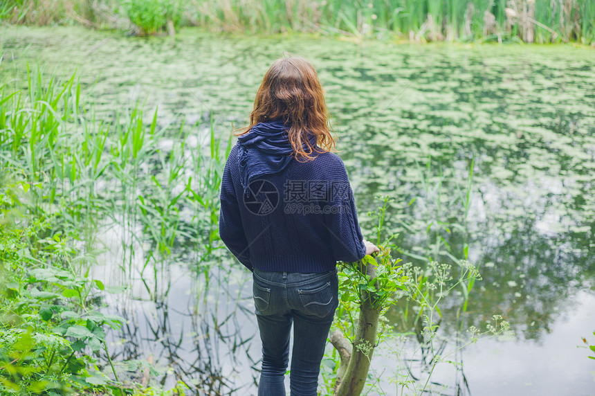 个轻的女人站森林里的池塘边图片