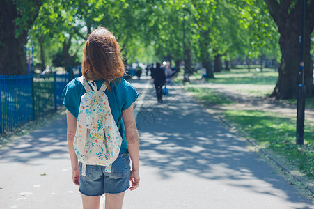 个轻的女人戴着顶烟袋,夏天的公园里站条小路上图片