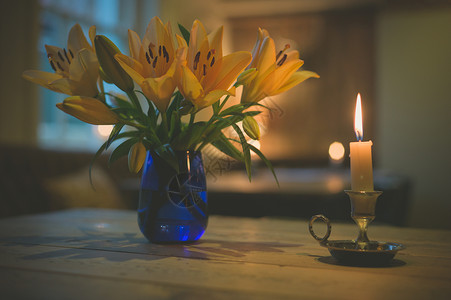 支点燃的蜡烛个花瓶,餐厅的桌子上放着盛开的百合花图片
