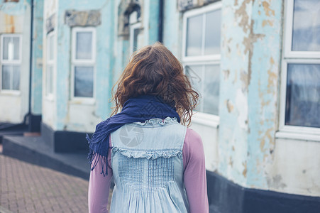个刮风的日子里,个轻的女人站海边所蓝色房子外的街上图片