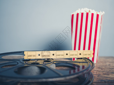 电影票爆米花电影的旧电影卷轴与爆米花电影票个木制的表背景