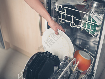 嵌入式洗碗机只轻的女手正把盘子放洗碗机里背景