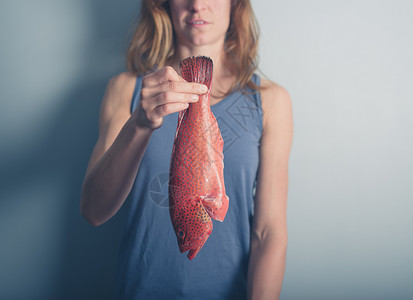 个轻的女人手里着条热带红黄鱼图片