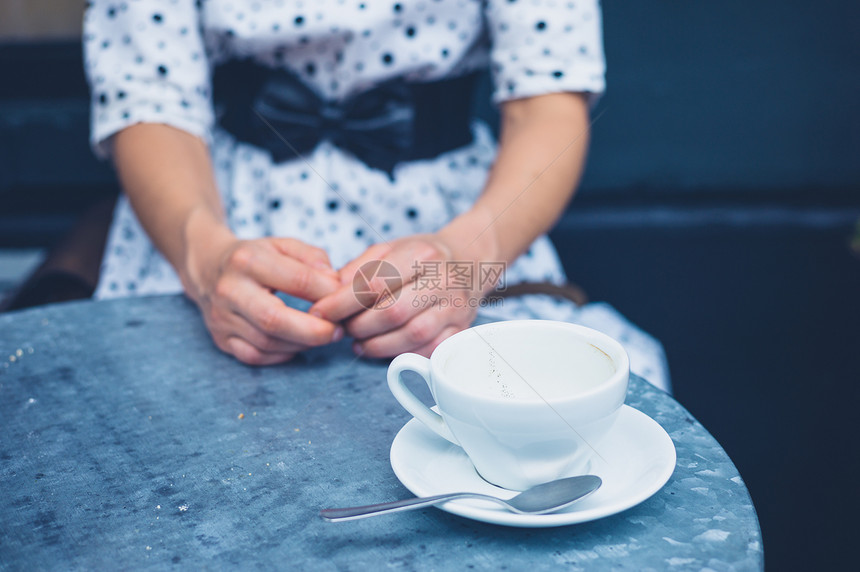 个轻的女人坐张空咖啡杯的桌子旁图片