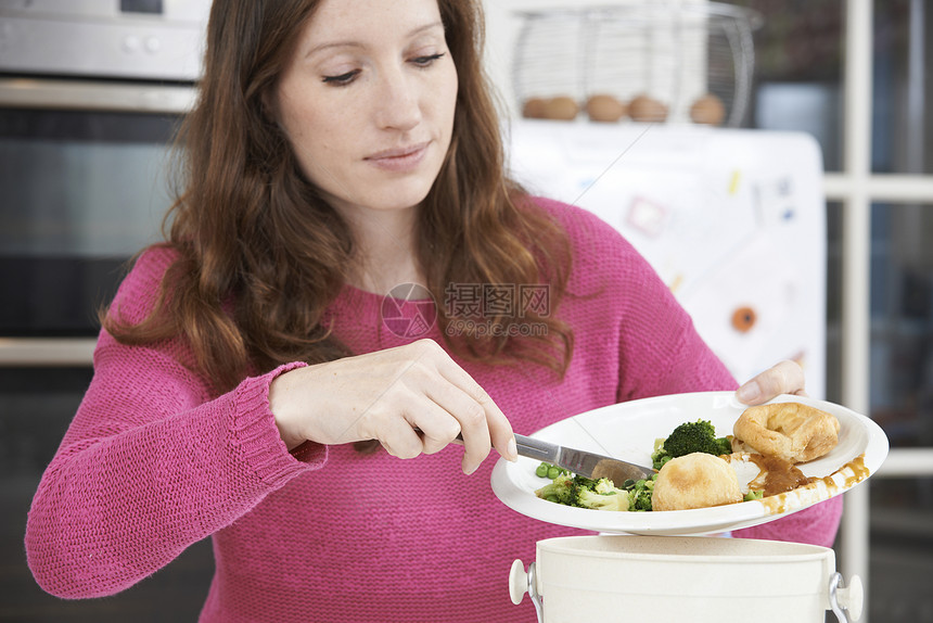 女人把食物剩菜刮进垃圾桶图片