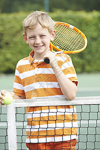 站网旁打网球的男孩的肖像图片