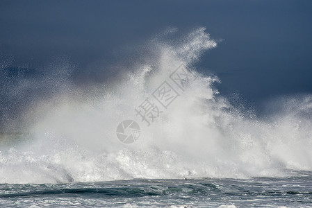 股巨大的波浪撞击着海洋中的个礁石,把水喷空中图片