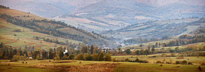 山间多云的秋天全景十月山谷的村庄图片