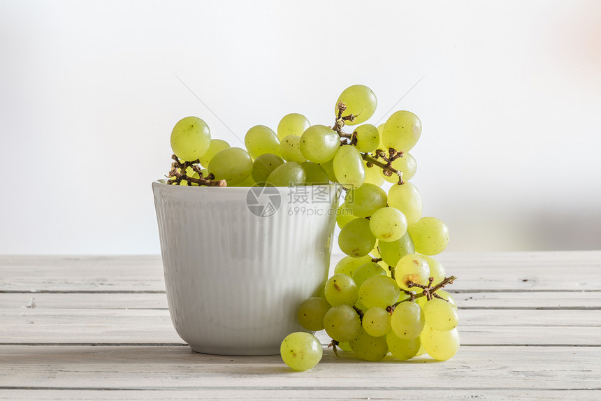木制桌子上绿色葡萄的白色碗图片