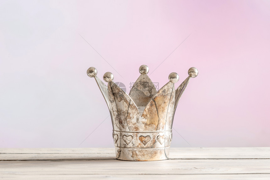 粉红色背景上的木桌上的皇家皇冠图片