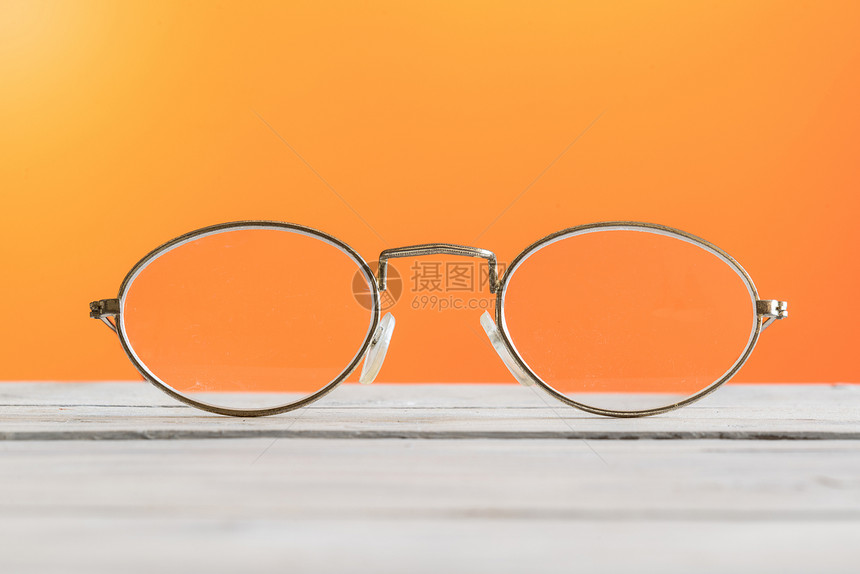 橙色背景的桌子上的眼镜图片