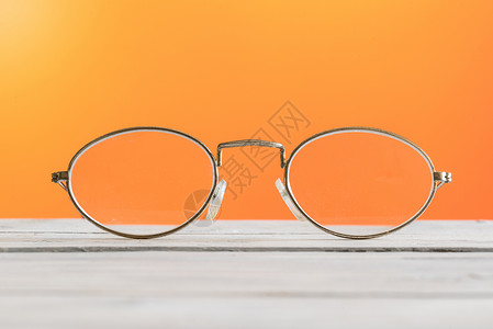 橙色背景的桌子上的眼镜图片