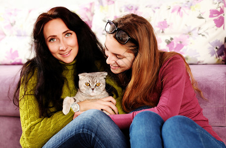 两个美丽的妹妹家里英国品种的宠物小猫玩耍室内,生活方式图片