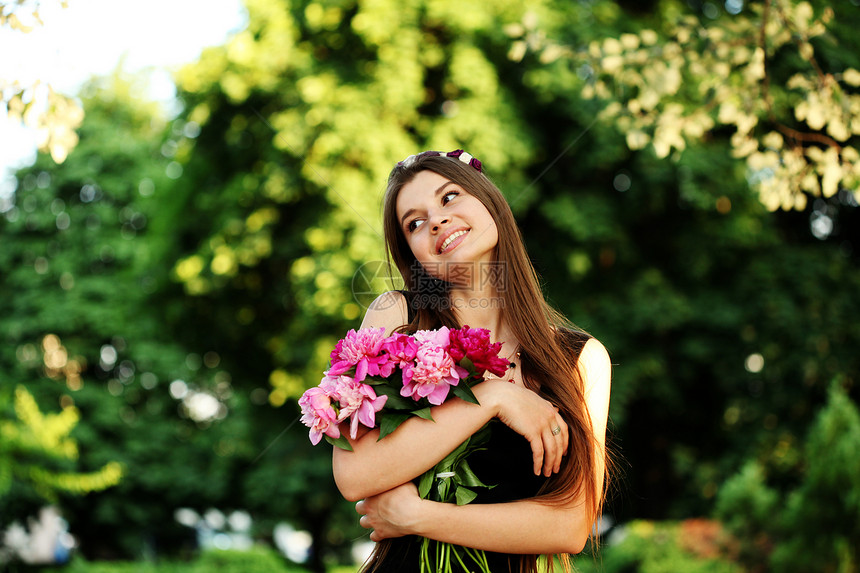 轻漂亮的女人穿着黑色的连衣裙,花园里摆着牡丹花时尚模特女孩,夏天户外花图片