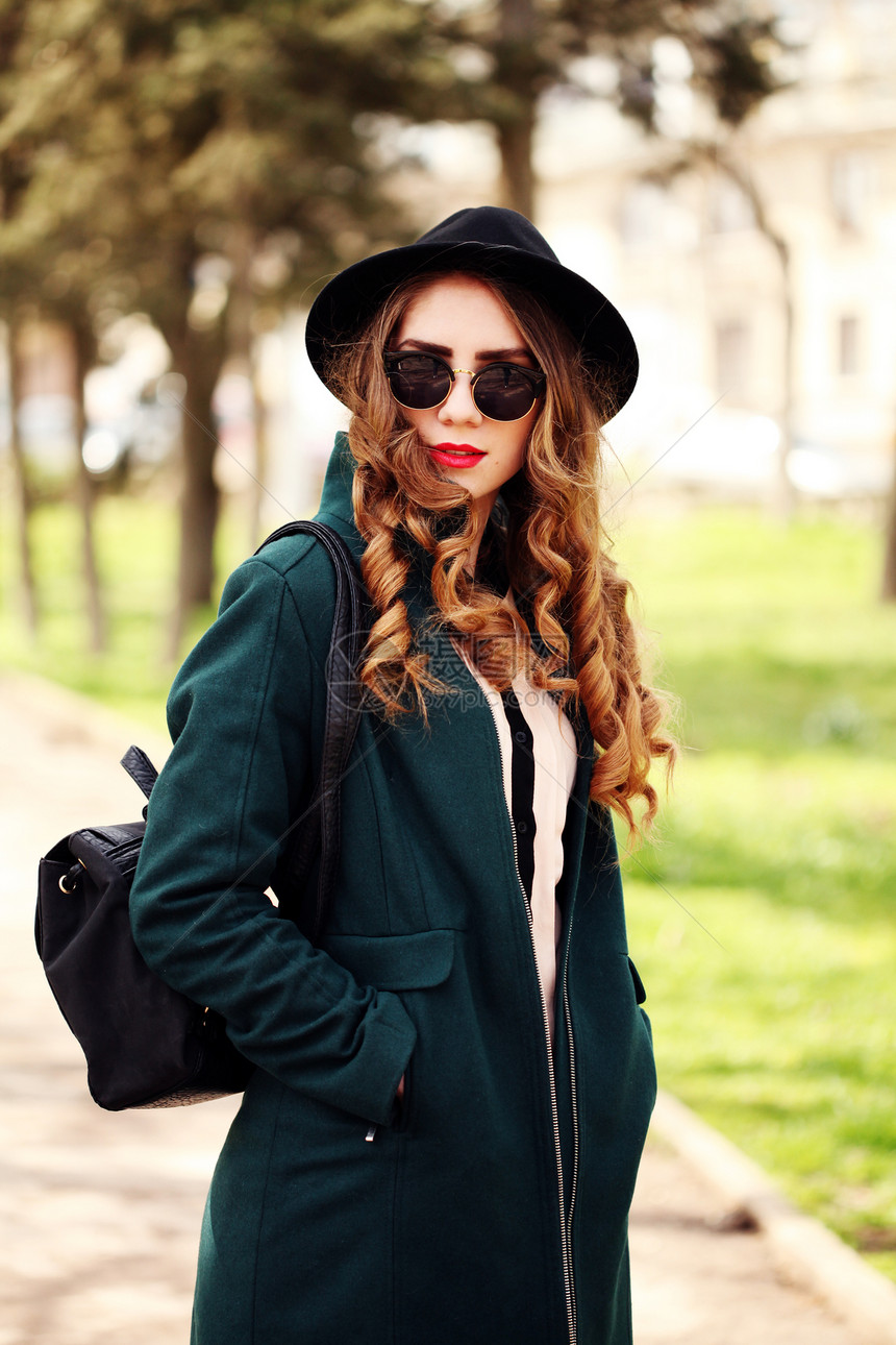 漂亮的轻时尚,微笑的金发女人,戴着太阳镜老式帽子,带着皮包,春天阳光明媚的天气里,绿色公园的背景下户外摆姿势时尚时图片