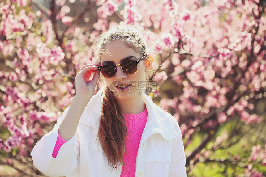时尚肖像,华丽的轻感金发女孩个郁郁葱葱的花园春天穿着时尚的白色夹克,粉红色衬衫条纹裙子太阳镜明亮的轻服装图片