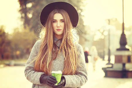 阳光生活方式的照片,轻时尚的时髦女人走街上,戴着可爱的时髦帽子,户外喝热铁咖啡时尚博主服装照片色调风格Insta背景图片