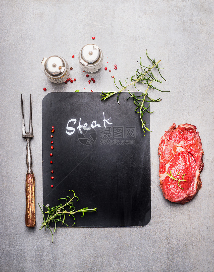 黑板烹饪背景与生牛排,肉叉,草药香料,顶部视图,地点为文本肉类食品图片