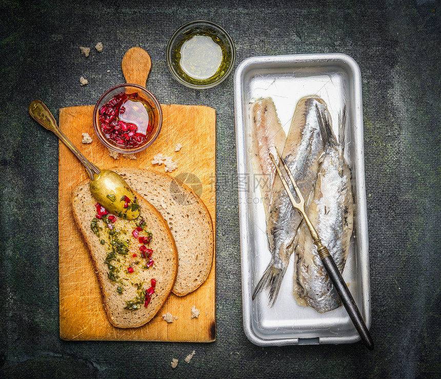 腌制的鲱鱼三明治与红色洋葱酱旧的切割板,顶部视图鱼的食物图片