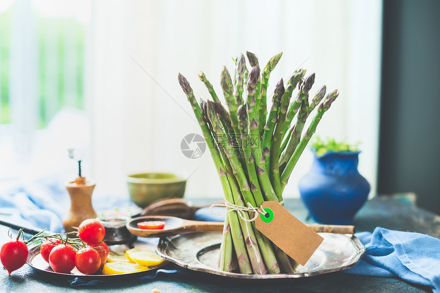 堆绿色芦笋,厨房桌子上烹饪蔬菜原料,窗户上白天的光线图片