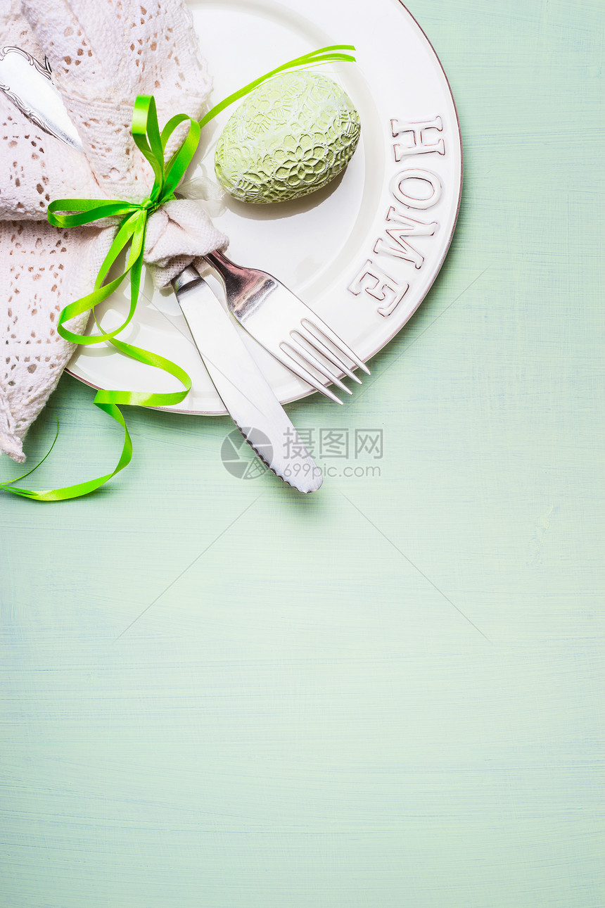 复活节餐桌与盘子,餐具装饰花边餐巾鸡蛋浅绿色背景,顶部视图文字复活节餐的地点图片