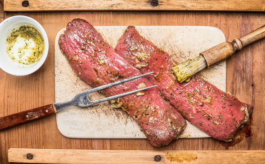 生肉片腌制与摩擦刷叉子木制背景,顶部视图图片