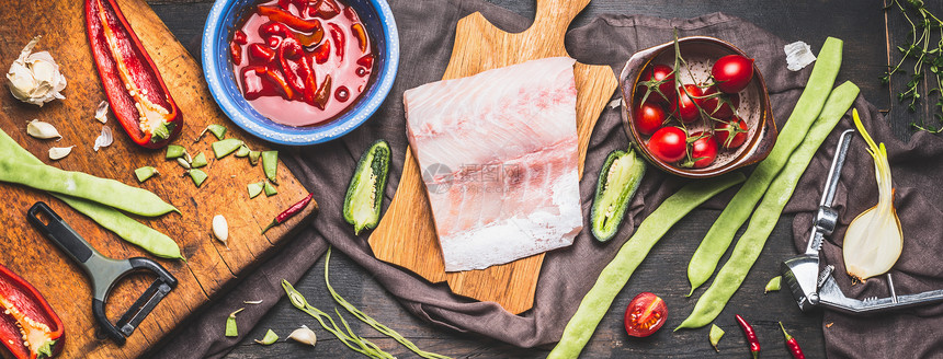 乡村砧板上的鱼片,季节蔬菜烹饪原料西红柿酱深色背景顶部视图横幅图片