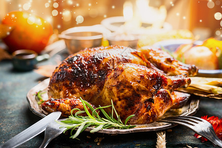 感恩节晚餐餐桌与整个烤火鸡鸡肉盘子与餐具,节日照明装饰,图片