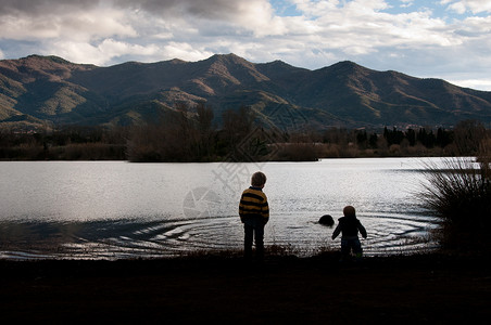 两个男孩个山湖上剪影高清图片
