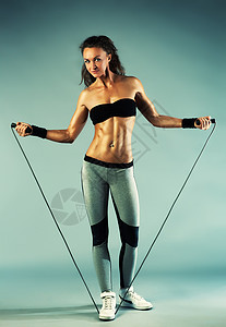 轻的体育感健身女子与跳绳墙上的背景图片