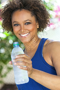 美丽的轻混血黑人非裔美国妇女,牙齿完美,微笑,锻炼喝瓶水外图片