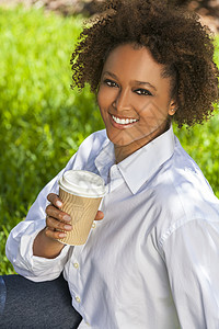 美丽的轻混血黑人非裔美国妇女,牙齿完美,微笑,公园夏天的阳光下喝咖啡茶图片