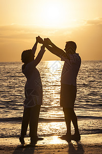 长的男女夫妇日落日出时荒芜的热带海滩上牵手跳舞图片