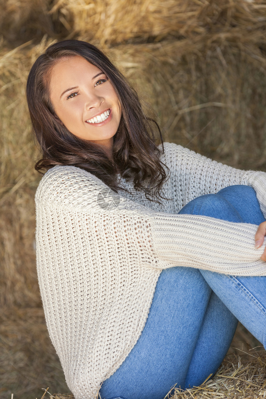 美丽快乐的亚洲欧亚青妇女女孩微笑着坐阳光下的干草堆谷仓图片