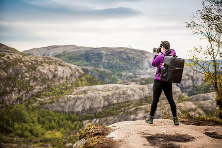 自然摄影师游客与相机拍摄,同时站山顶美丽的自然挪威图片
