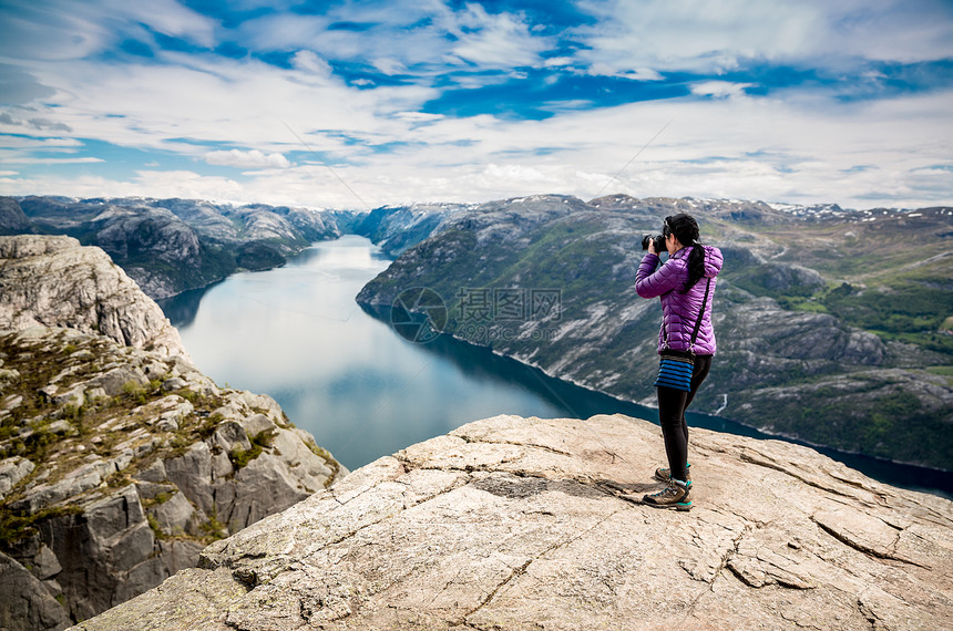 自然摄影师游客与相机拍摄,同时站山顶美丽的自然,挪威的前客前客图片