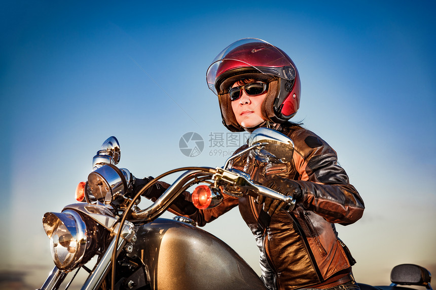 骑摩托车的骑自行车的女孩穿着皮夹克头盔图片